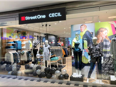 Innenansicht eines Modegeschäfts mit Kleidung und Modellen der Marke Street One CECIL.