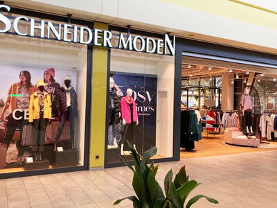 Ladenfront von Schneider Moden mit Kleidung im Inneren.