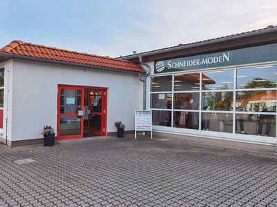 Außenansicht eines Schneider-Moden Outlets mit roten Eingängen.