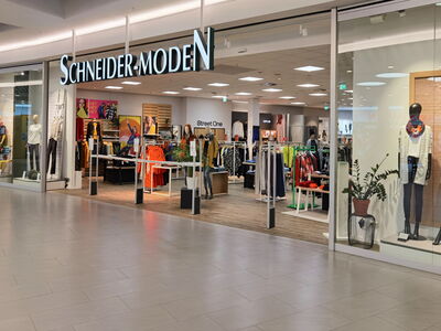 Innenansicht eines Modegeschäfts mit Kleidung und der Aufschrift Schneider-Moden.