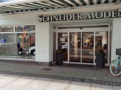 Schaufenster des Ladens Schneider Moden mit Fahrrad im Vordergrund.